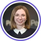 A headshot of a smiling short haired brunette woman wearing glasses and a collared black jumper with a purple ring around the image.